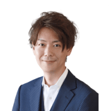 こちらを向いて微笑むジャケット姿の男性の写真