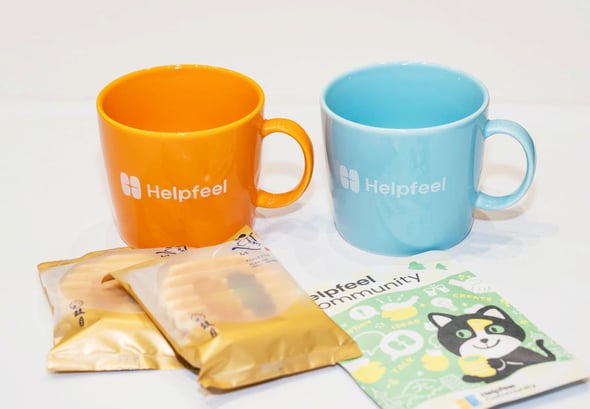 後ろにオレンジ、ブルーのマグカップ、手前にお菓子とお茶がある