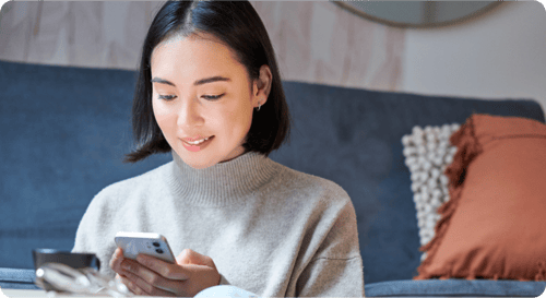 ソファに座ってスマートフォンを見つめる女性
