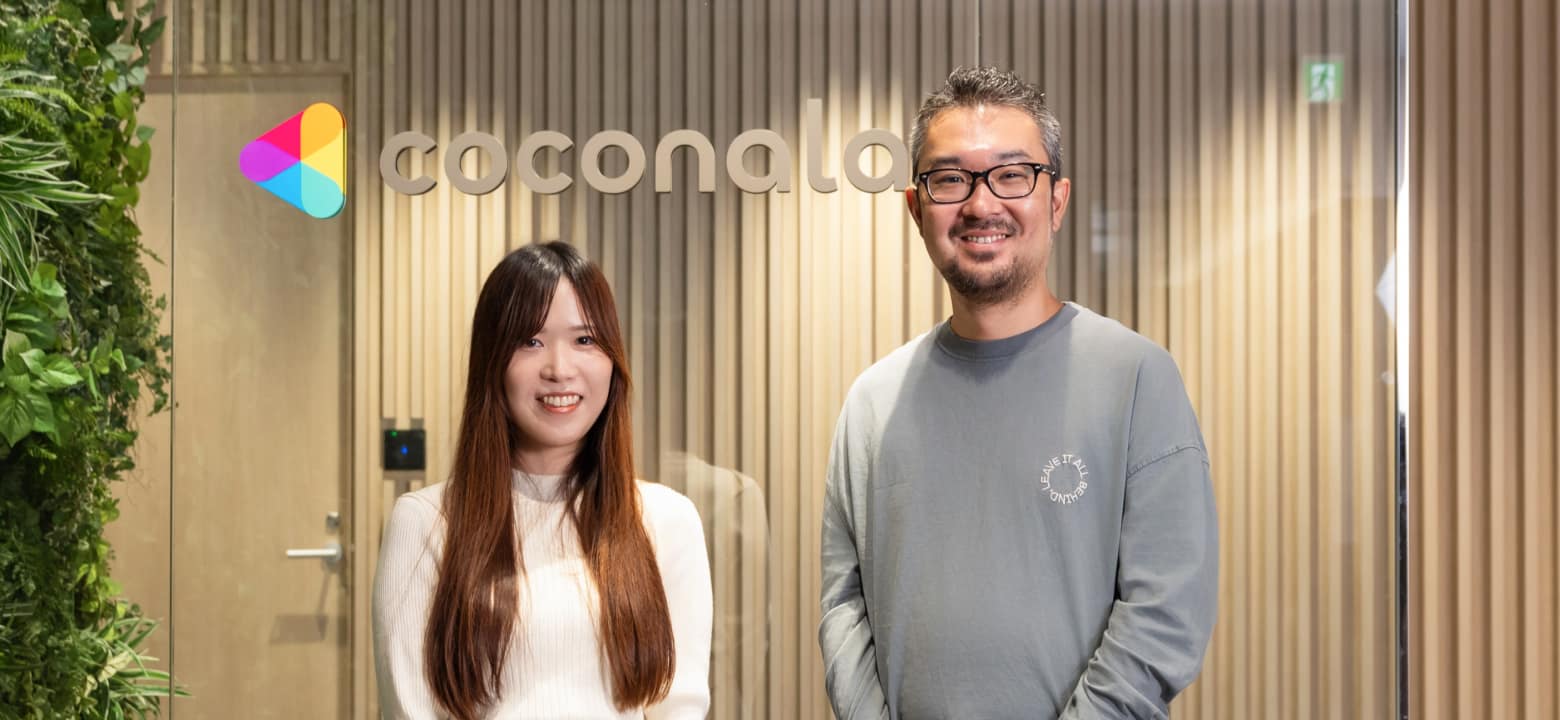 coconalaのロゴの前で微笑む男女