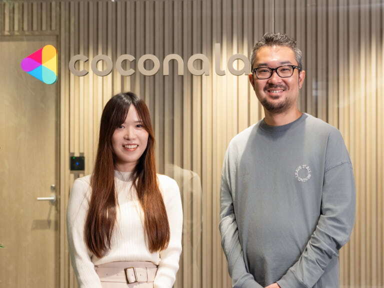 coconalaのロゴの前で微笑む男女