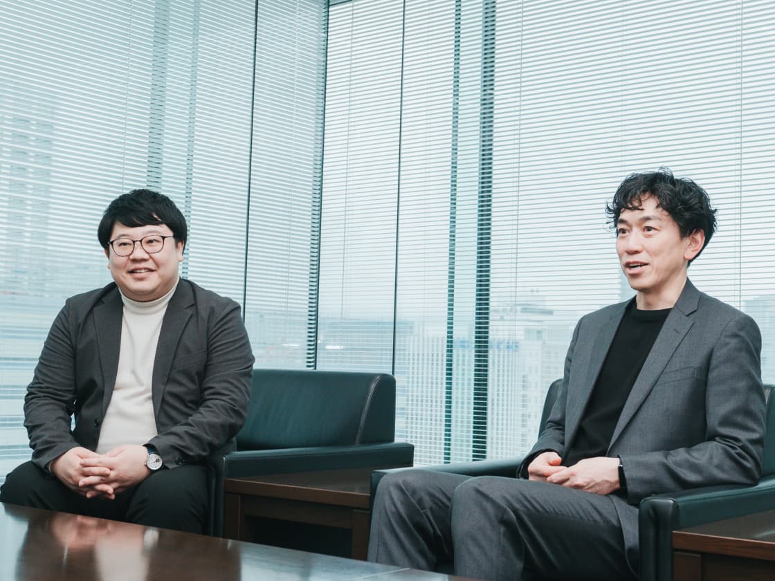 大きな窓のある会議室で、笑顔でインタビューに応じる北洋銀行のご担当者2名の写真