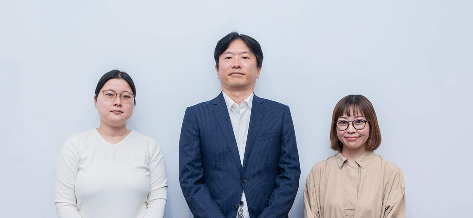 白い壁の前に立つ2人の女性と1人の男性